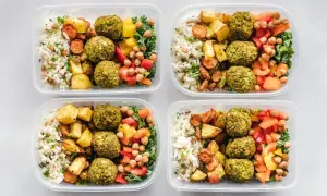 Cztery pojemniki z posiłkami: ryż, pieczone ziemniaki, falafel, warzywa i ciecierzyca.