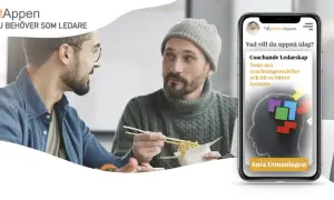 Två män äter lunch och pratar. En mobil visar appen MakeitAppen med en utmaning för coachande ledarskap, ett bra sätt att visa uppskattning på jobbet.