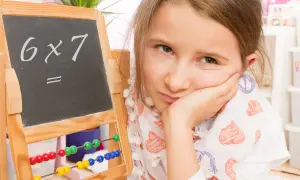 Mädchen mit gelangweiltem Gesichtsausdruck vor einer Tafel mit "6x7=". Vielleicht hilft die Trachtenberg-Methode beim Rechnen.