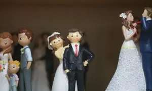 Figurines de couples mariés, certaines avec des enfants, sur un fond flou.