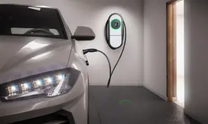 Auto elettrica in ricarica in un box privato. Stazione di ricarica a muro e cavo collegato. Luce verde sul pavimento indica la posizione.