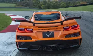 Pomarańczowy Corvette C9 z dużym spojlerem na torze wyścigowym.