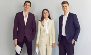 Trzy uśmiechnięte osoby w eleganckich strojach. Idealny przykład, co ubrać na rozmowę kwalifikacyjną.