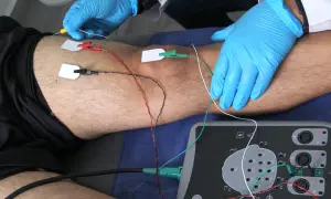 Elektrody podłączone do nogi pacjenta i aparat do badań.