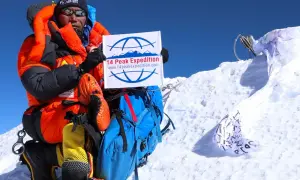 Kami Rita feiert auf dem Gipfel mit einem Schild der "14 Peak Expedition".