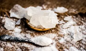 Kryształki ałunu potasowego, znanego jako potassium alum co to, rozsypane na drewnianym tle.