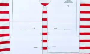 Wzór wykroju na bluzkę typu bretońskiego leży na materiale w biało-czerwone paski. Dzianina w paski idealnie pasuje do morskiego stylu.
