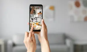 Dłonie trzymają telefon, na którym widać podgląd z kamer: salon, sypialnię i pomieszczenie z rowerem. To wygodne nagrywanie na telefonie.