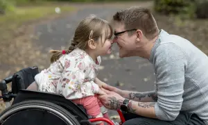 Padre e figlia si toccano il naso, lei in carrozzina. Un momento di gioia che celebra i diritti genitori con figlio disabile.