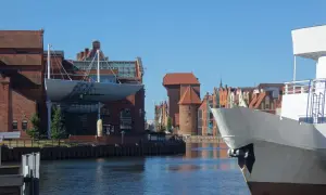 Widok na Motławę podczas weekendu w Gdańsku. Biały kadłub statku na pierwszym planie, w tle zabytkowe kamieniczki i Żuraw.