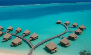 Bora Bora, Polinezja Francuska: domki na wodzie z krytymi strzechą dachami, połączone drewnianymi pomostami, w turkusowej lagunie.