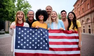 Grupo de jóvenes sonriendo y sosteniendo la bandera de EE.UU. ¡Un año de intercambio en Estados Unidos lleno de alegría!