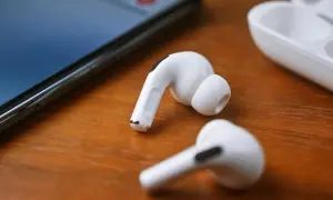 Białe słuchawki JBL leżą obok iPhone'a i etui. Dowiedz się, jak podłączyć słuchawki JBL do iPhone'a, by cieszyć się muzyką.