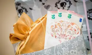 Złota sakiewka z prezentem i banknotami 10 euro, ozdobiona koronkową kartką. Idealny pomysł, jak zapakować zdrapki na wesele.