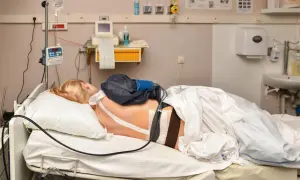 Kobieta w łóżku szpitalnym, przygotowana do porodu. Znieczulenie do porodu podawane przez pompę infuzyjną.