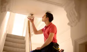 Un homme vérifie un détecteur de fumée, essentiel pour la différence entre détecteur de fumée et monoxyde de carbone.