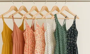 Letnie sukienki na wieszakach: musztardowa, łososiowa, w pomarańczowe kwiatuszki, w grochy, zielona i granatowa. Czy spandex oddycha? Te materiały wyglądają na przewiewne.