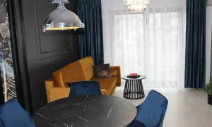 Eleganckie wnętrze z musztardową kanapą i granatowymi krzesłami. Idealne miejsce na tanie noclegi Dziwnów.