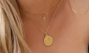 Elegante cadena de oro con medalla de San Benito y un pequeño crucifijo.