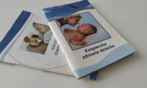 Dwie książeczki zdrowia dziecka leżą na białym tle. Jedna z nich przedstawia matkę całującą niemowlę, druga śpiące dziecko z misiem.