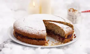Torta di grano saraceno trentino con marmellata, spolverata di zucchero a velo, su un letto di neve e candele accese.
