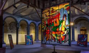 Vetrate colorate e quadri astratti in una galleria d'arte, con un'opera di ara starck al centro.