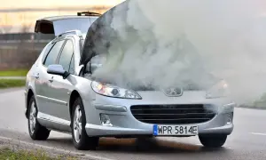 Srebrny Peugeot z otwartą maską i kłębami dymu. Chyba ten rozbiegany diesel potrzebuje pomocy.