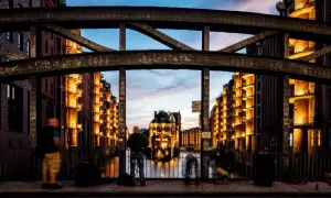 Spektakuläre Fotografie Hamburg: Speicherstadt im Abendlicht, beleuchtete Backsteingebäude spiegeln sich im Wasser.