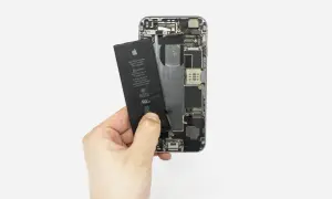 Dłoń wyjmuje baterię z otwartego iPhone'a 6s.