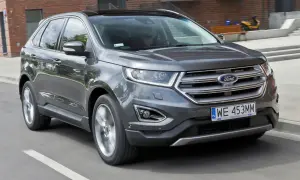 Szary Ford Edge w ruchu miejskim. Kierowca zadowolony, co potwierdzają pozytywne ford edge opinie.