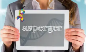 Kolorowa wstążka symbolizuje zespół Aspergera na ekranie tabletu, który trzyma osoba w szarym żakiecie.