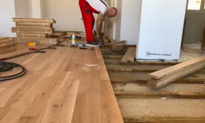Instalador coloca elondo madera en un suelo.