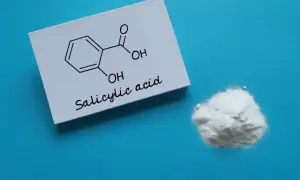 Kwas salicylowy na twarz: biały proszek i jego wzór chemiczny na kartce.