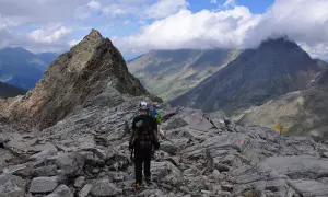 Wanderer auf einem steinigen Grat, mit Blick auf den wilden Freiger und dramatische Wolken.