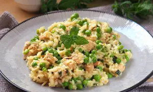Pyszne risotto z groszkiem i kawałkami kurczaka, udekorowane listkiem mięty. Idealne na lekki obiad.