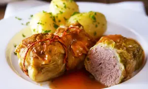 Herzhafte Kohlrouladen mit Kartoffeln, ein Klassiker der deutschen Gerichte, serviert auf einem weißen Teller.