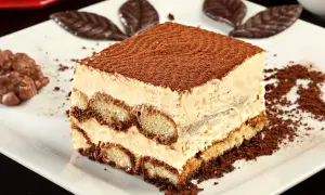 Pyszne tiramisu, idealne na prosty przepis na ciasto cappuccino. Warstwy biszkoptów i kremu, posypane kakao.