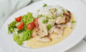 En krämig kycklinggryta med bacon, serverad med ris och en fräsch sallad av sallad, tomat och gurka.