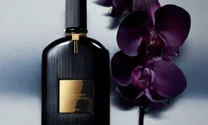 Elegancka butelka perfum Tom Ford Black Orchid 100ml obok ciemnofioletowych storczyków.