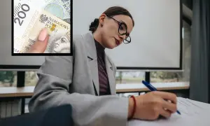 Dyrektor szkoły analizuje dokumenty, zastanawiając się, ile zarabia. W tle widać banknot 200 zł.