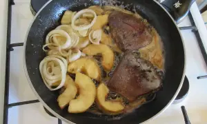 Leber braten: Zwiebelringe und Apfelspalten in der Pfanne mit der Leber garen.