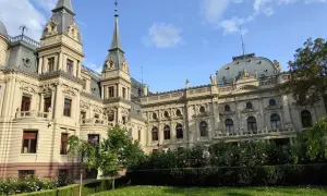 Imponujący pałac poznańskiego, z wieżyczkami i bogatymi zdobieniami, otoczony zielonym ogrodem z kwitnącymi różami.