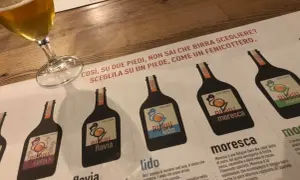Un bicchiere di birra e un menu del birrificio Rubiu con diverse etichette di birra.