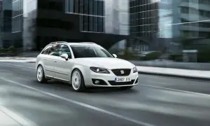 Biały Seat Exeo 2.0 TDI kombi pędzi ulicą miasta, mijając nowoczesne budynki.
