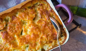 Goldbraun überbackener Kartoffel Zucchini Auflauf in einer Auflaufform, bereit zum Servieren.