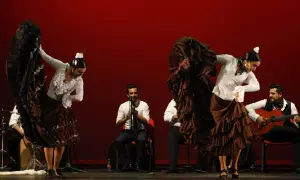 Bailarinas de flamenco con volantes, guitarrista y percusionista. La pasión del flamenco, su saeta significado, cobra vida en el escenario.