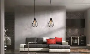 Nowoczesna ściana działowa z betonową fakturą oddziela salon od kuchni. Dwa industrialne lampy wiszące nad kanapą.