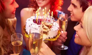 Amigos celebran con pastel y copas de champán. ¡Así se escribe happy birthday en español: ¡Feliz Cumpleaños!
