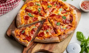 Pyszna pizza gourmet z pepperoni, ciągnącym serem i świeżą bazylią, podana na drewnianej desce.