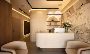 Nowoczesne wnętrze recepcji kliniki dermatologii estetycznej z kamienną ścianą i wygodnymi fotelami.